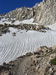 Windblown snow drifts below the trail